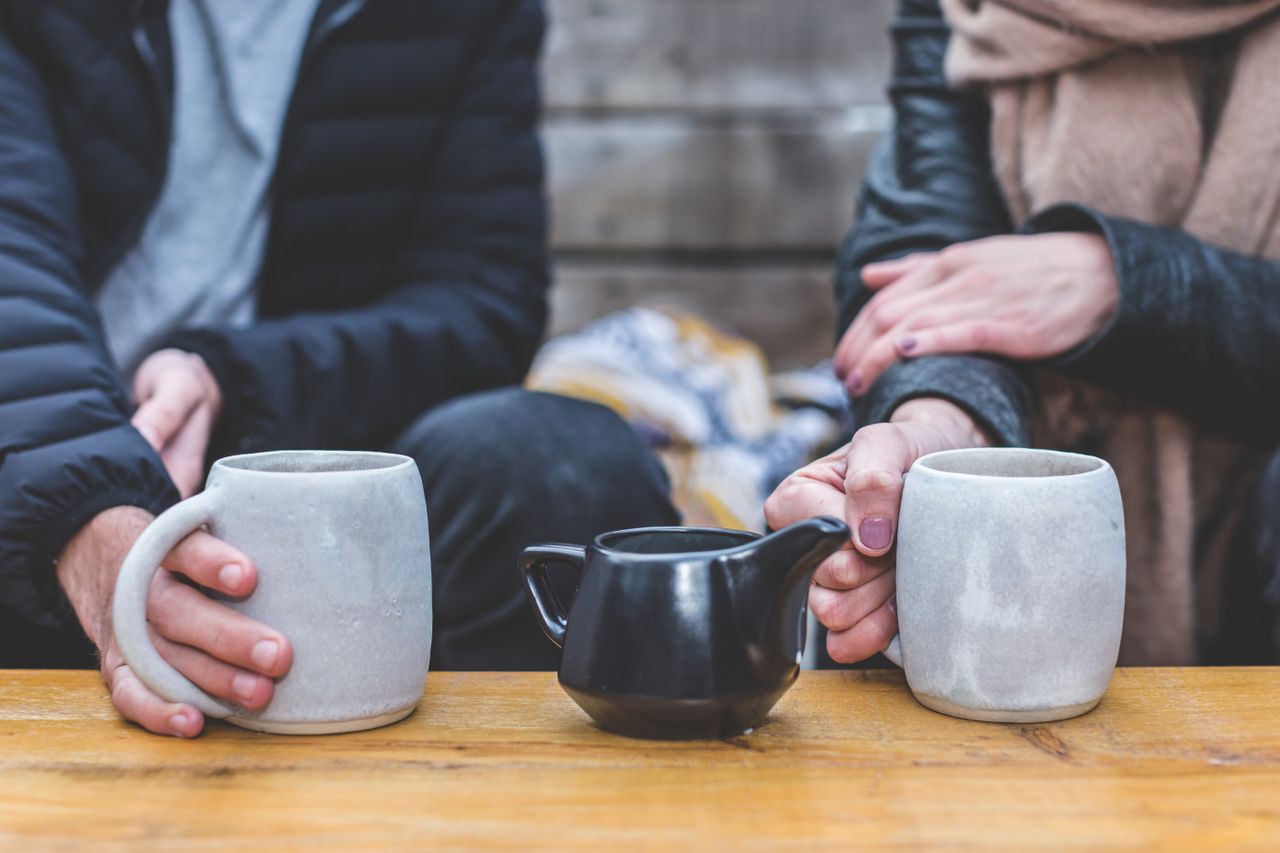 Couple sharing mugs of tea at an outdoor table