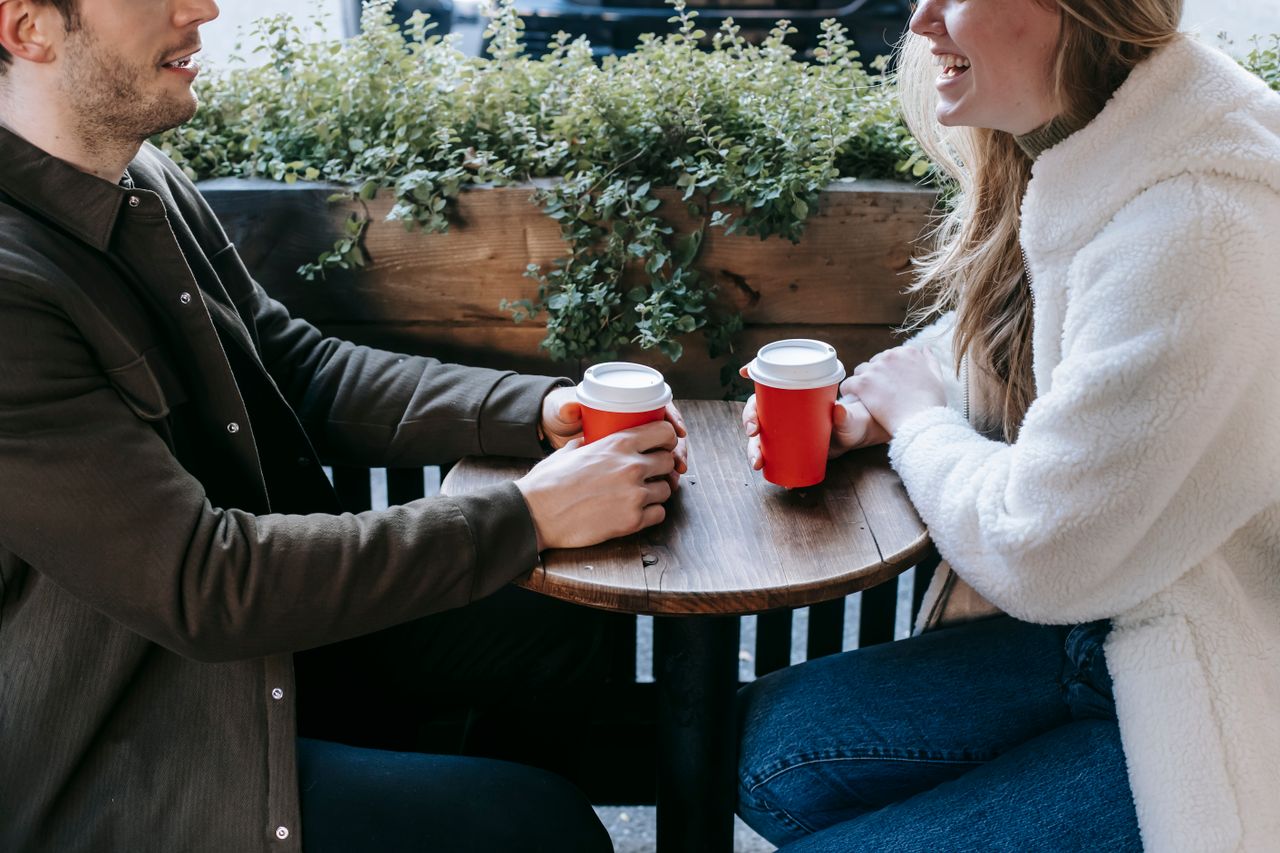 Couple with takeaway cups making eye contact at a table